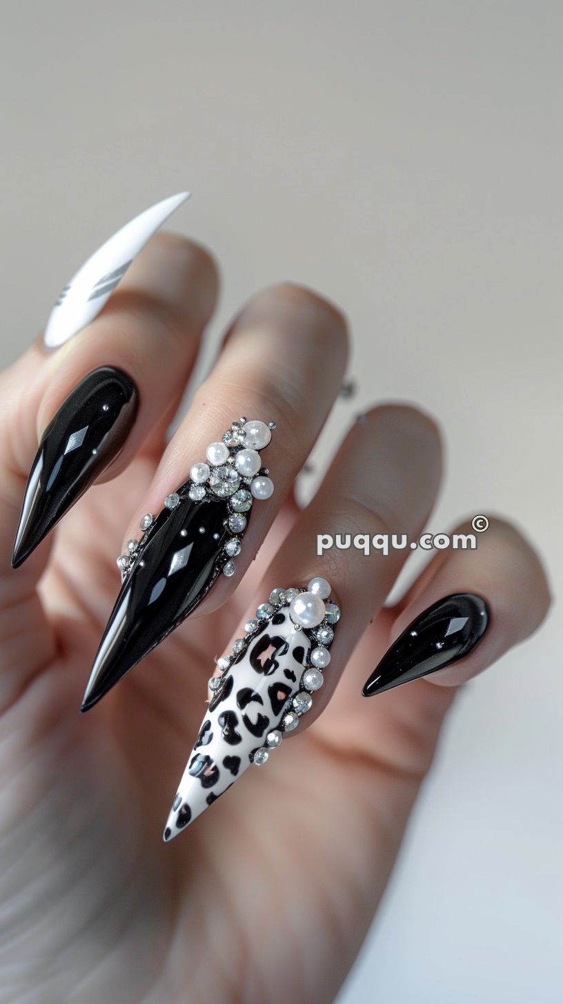 Long, stiletto-shaped nails with black, white, and animal print designs, adorned with pearls and rhinestones.