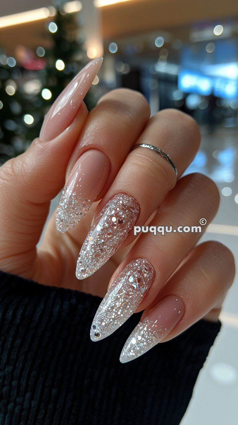 Long almond-shaped nails with a pink base and silver glitter gradient tips.