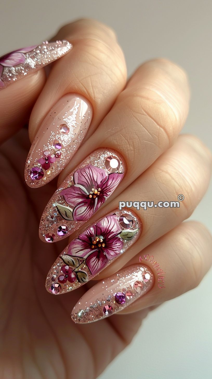 Long nails with pink polish, adorned with glitter, rhinestones, and hand-painted intricate floral designs.