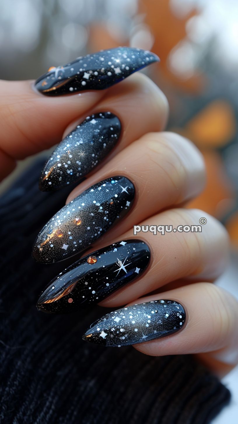 Close-up of a hand featuring black stiletto nails with a galaxy design, including white stars and small dots resembling stars.