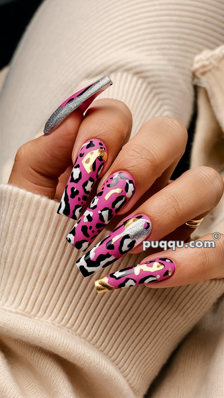 Hand with long pink nails featuring black and white leopard print design and gold accents.