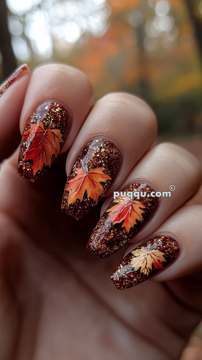 Close-up of glittery autumn-themed nail art with maple leaf designs.
