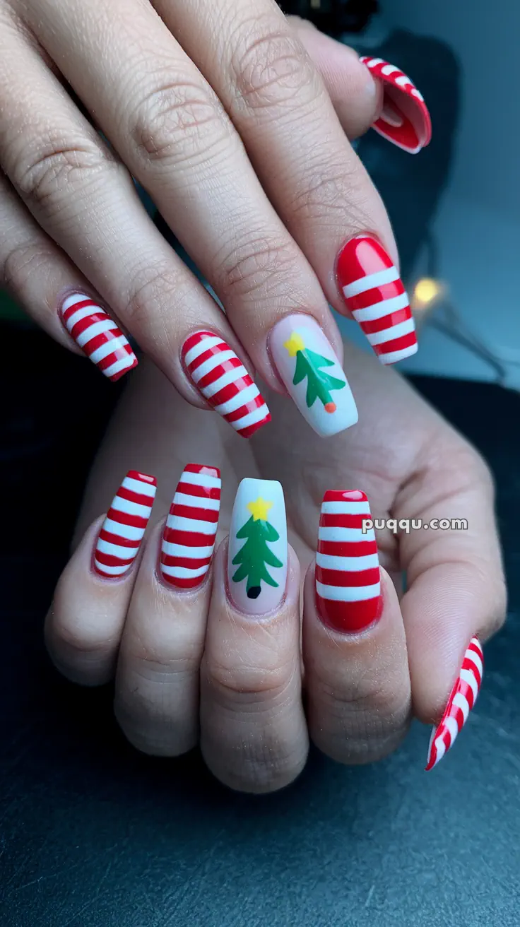 Close-up of festive nails with red and white stripes and Christmas tree designs.