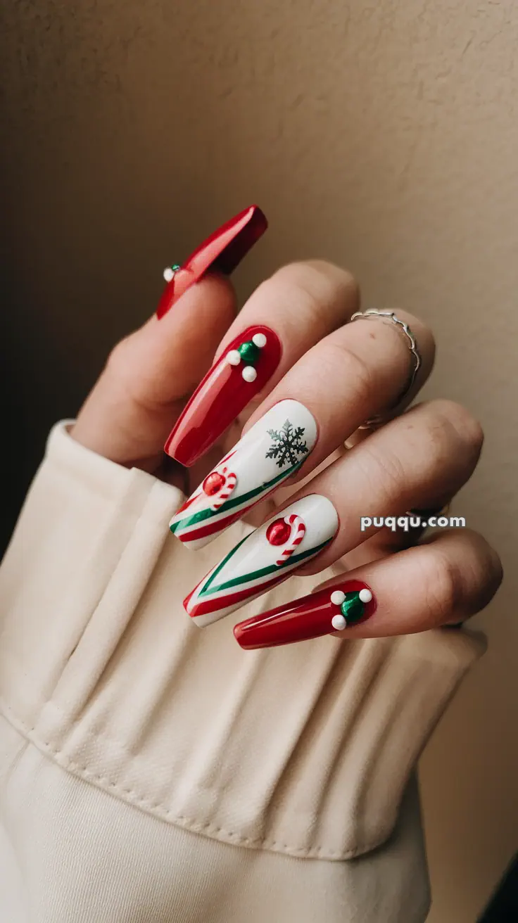 Hand with festive red and white Christmas-themed nail art featuring snowflakes, candy canes, and decorative beads.