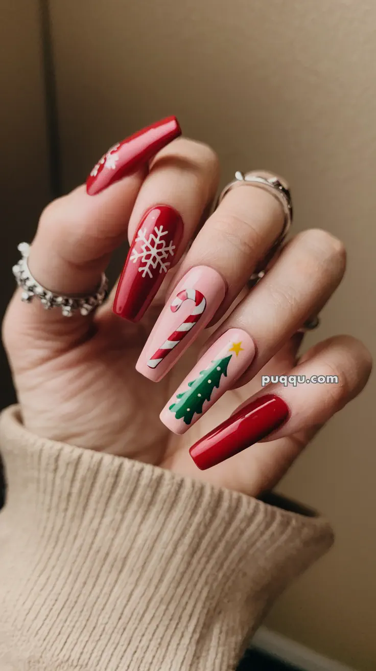Close-up of a hand with festive nail art, featuring red nails with snowflakes, and nude nails with a candy cane and Christmas tree design.