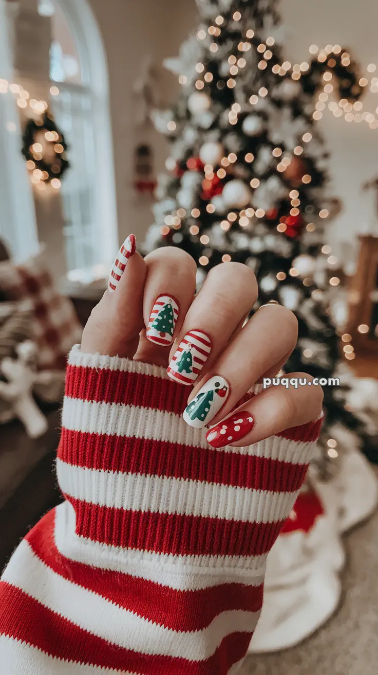 Christmas-themed nail art featuring trees, stripes, and polka dots, with a blurred Christmas tree in the background.