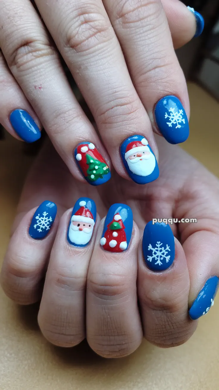 Blue Christmas-themed nail art with Santa, snowflakes, and a Christmas tree.