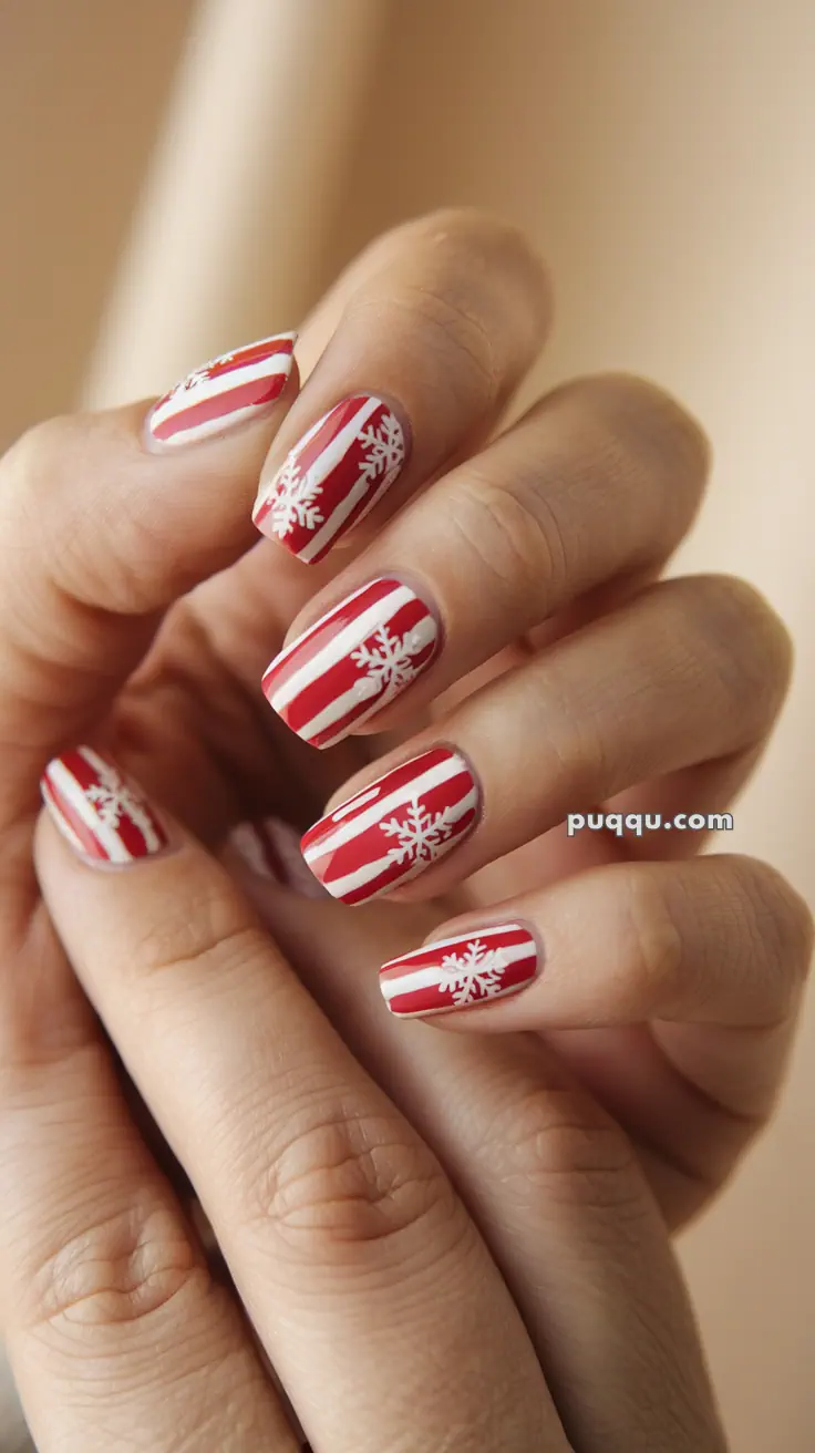Red and white striped nails with snowflake designs.
