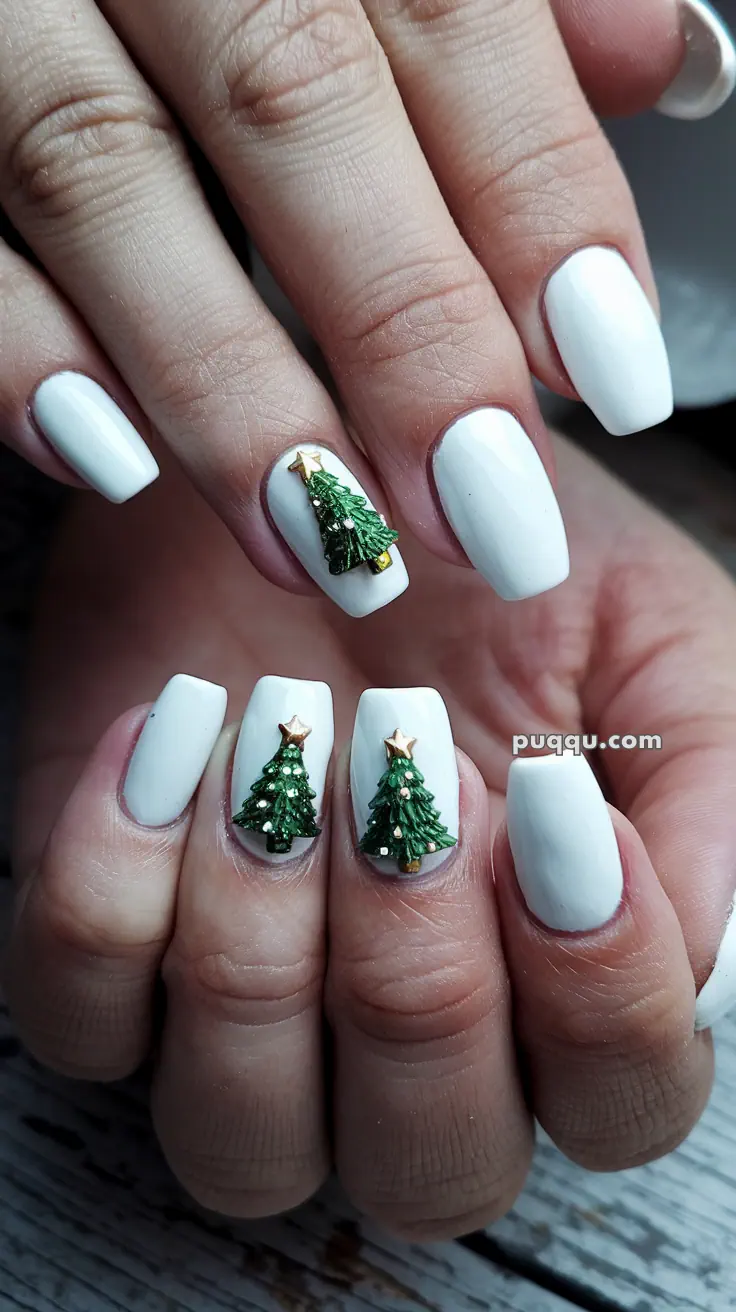 White manicured nails with 3D Christmas tree embellishments on middle fingers.
