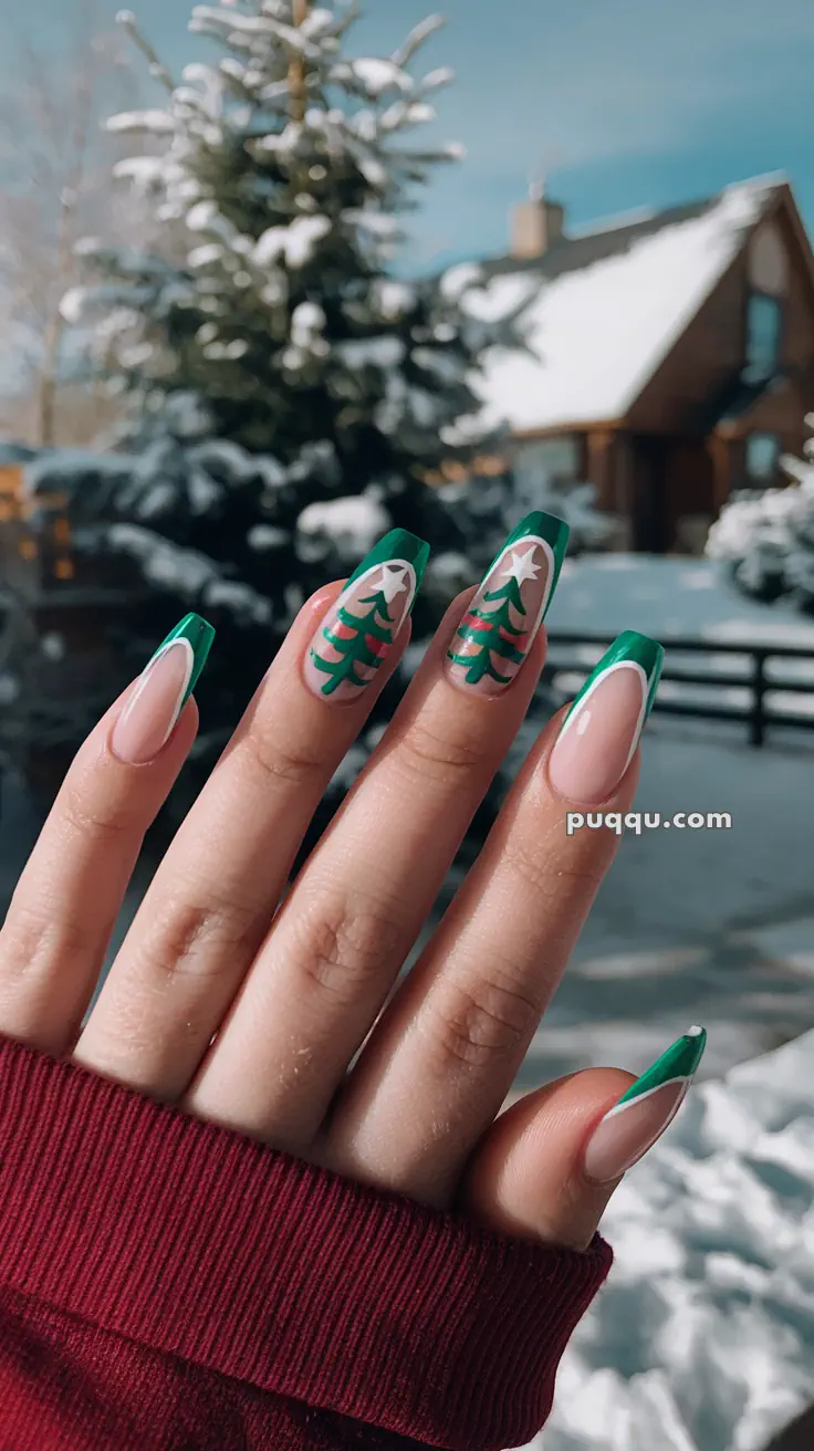 A hand with Christmas-themed nails featuring fir tree designs, set against a snowy outdoor background with a cabin and fir trees.
