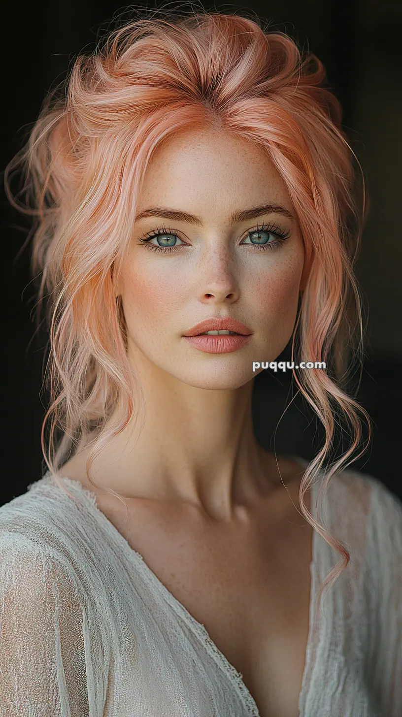 A woman with wavy pink hair and a neutral expression, wearing a light, textured blouse.