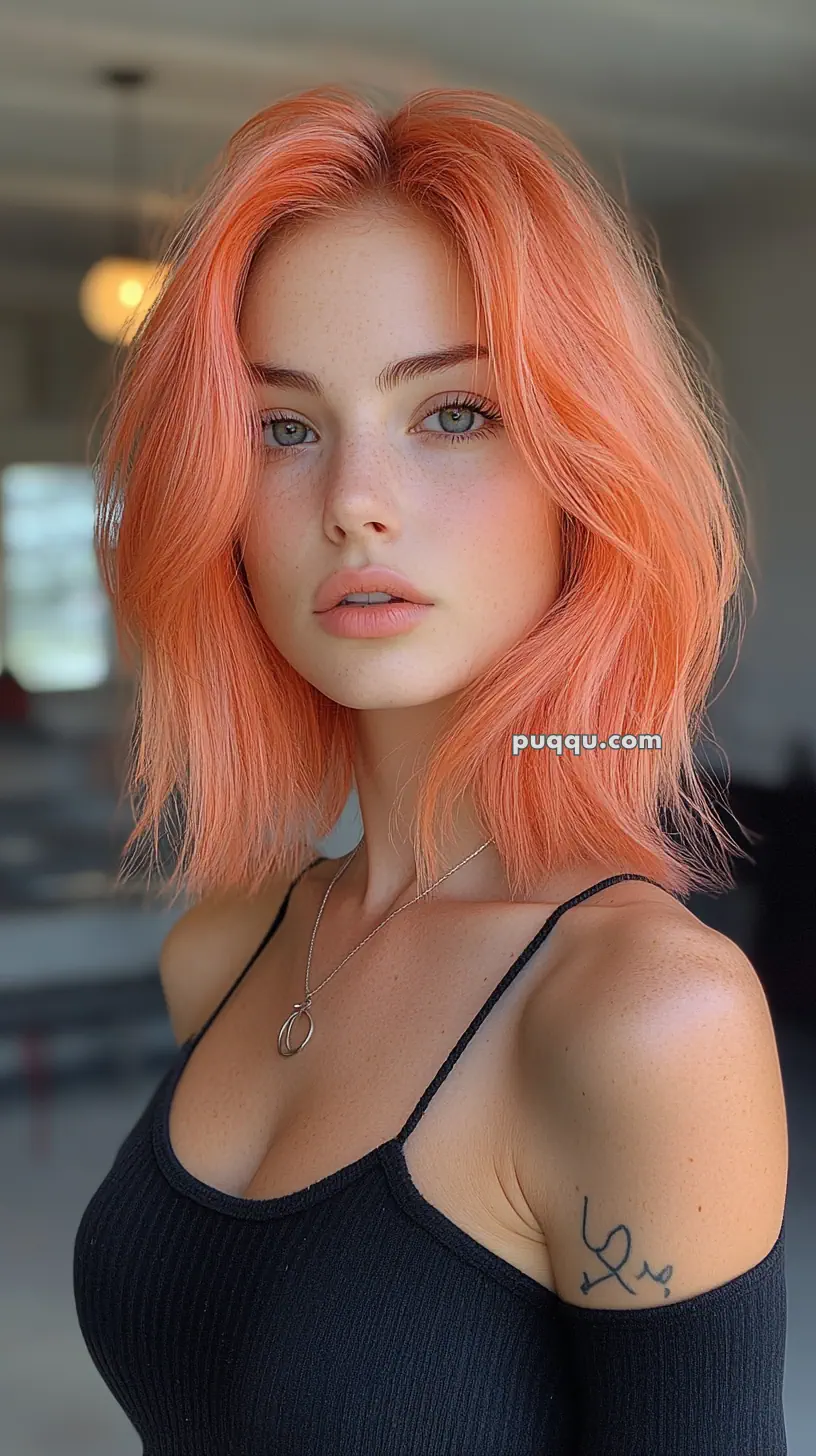 A woman with orange hair and a tattoo on her arm, wearing a black top.